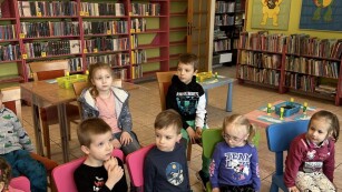 grupa dzieci siedzi na kolorowych plastiowych krzesekach