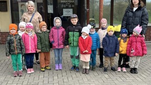 Grupa dzieci z opiekunkami stoją przed wejściem do miejskiej  biblioteki publicznej  w Lublinie na ulicy Juranda